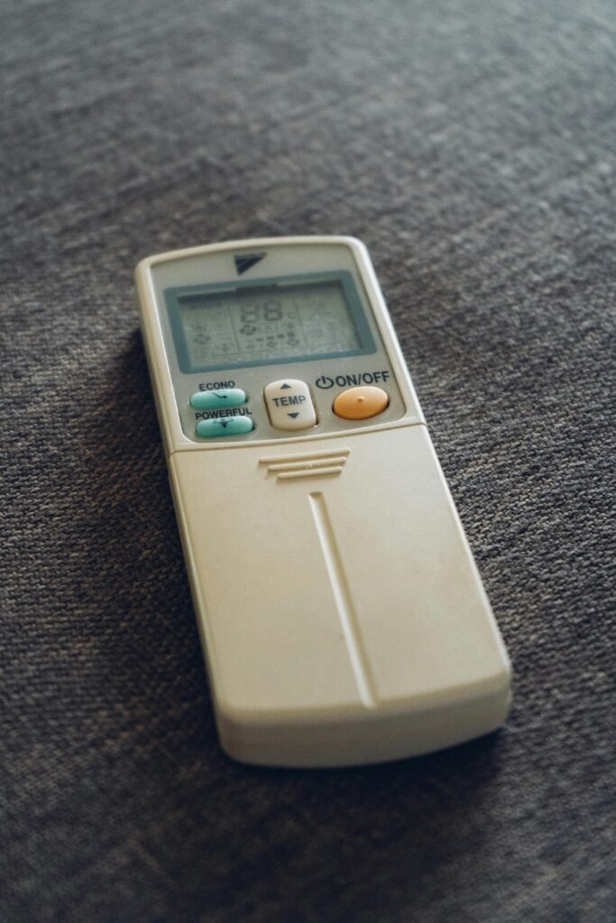A close-up view of an air conditioner remote resting on a textured fabric surface.